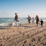 Howard Johnson Oceanfront Inn family playing on the beach with their leashed dog